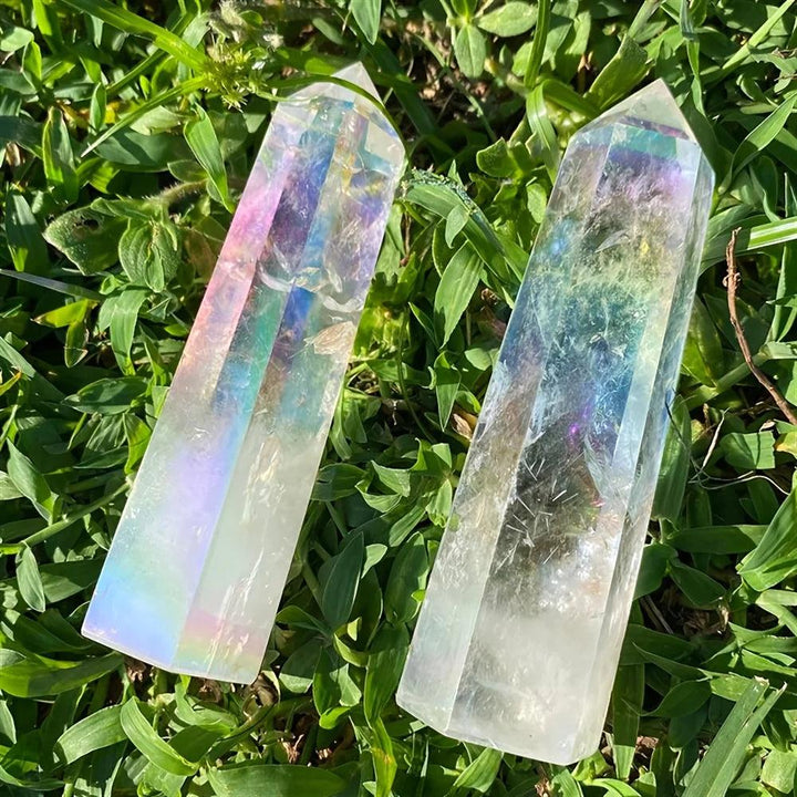 Iridescent electroplated clear quartz crystal stone towers with healing aura glow on green grass.