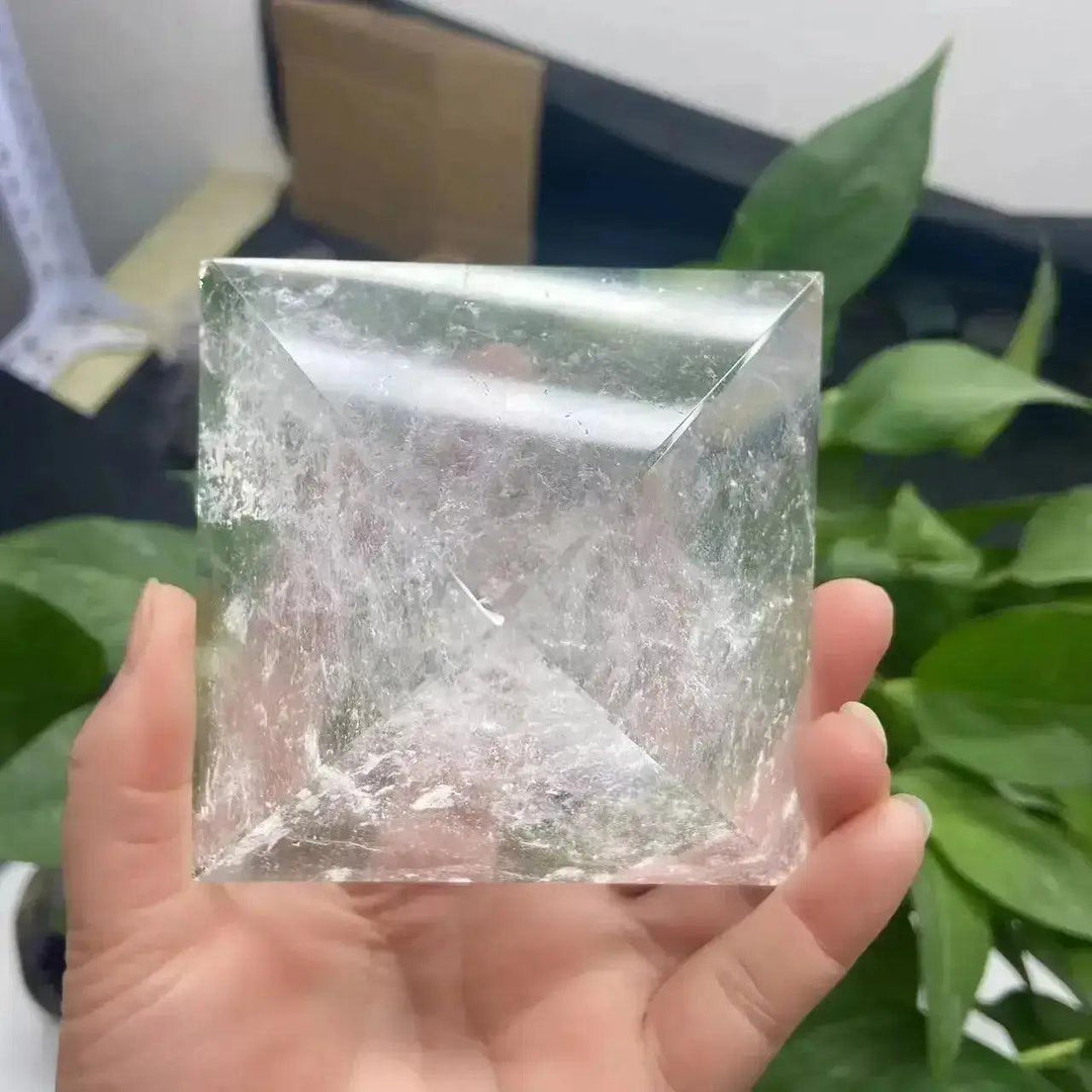 Hand holding a clear quartz crystal pyramid, a natural amplifier stone for clarity and focus.