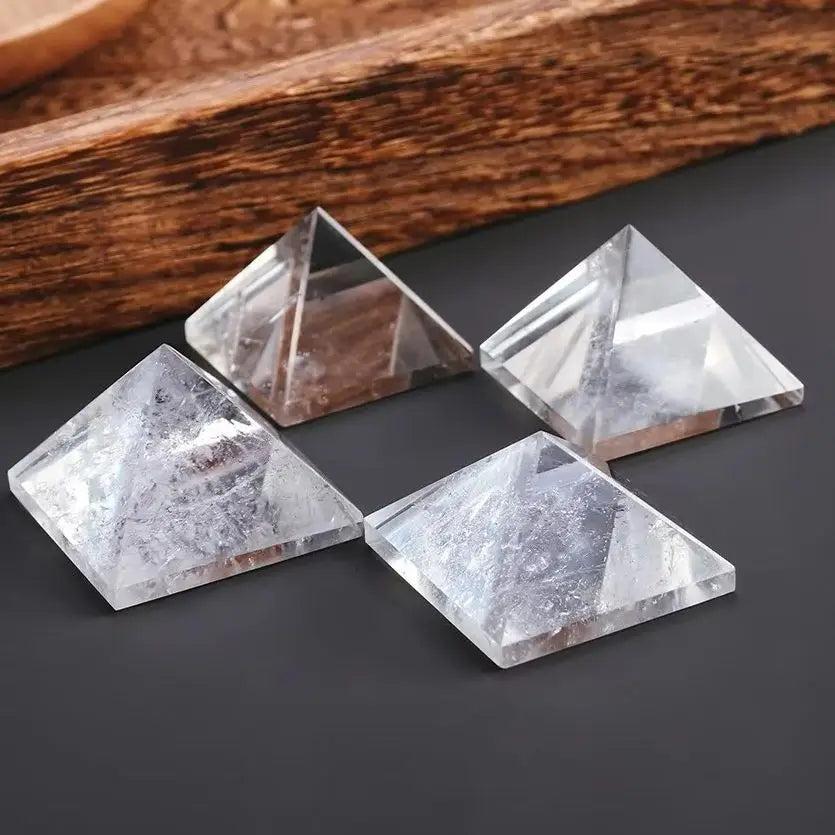 Four clear quartz crystal pyramids for chakra healing and meditation, on a dark surface.