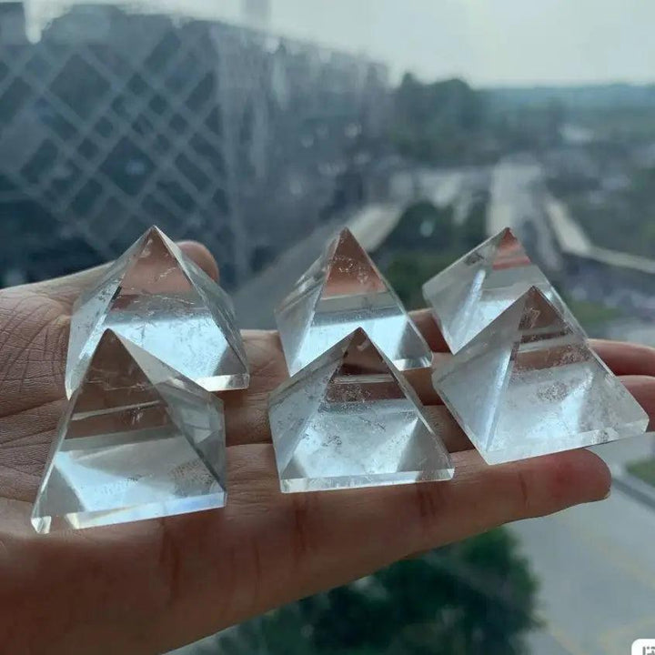 Hand holding five clear natural quartz crystal pyramids for healing and meditation.