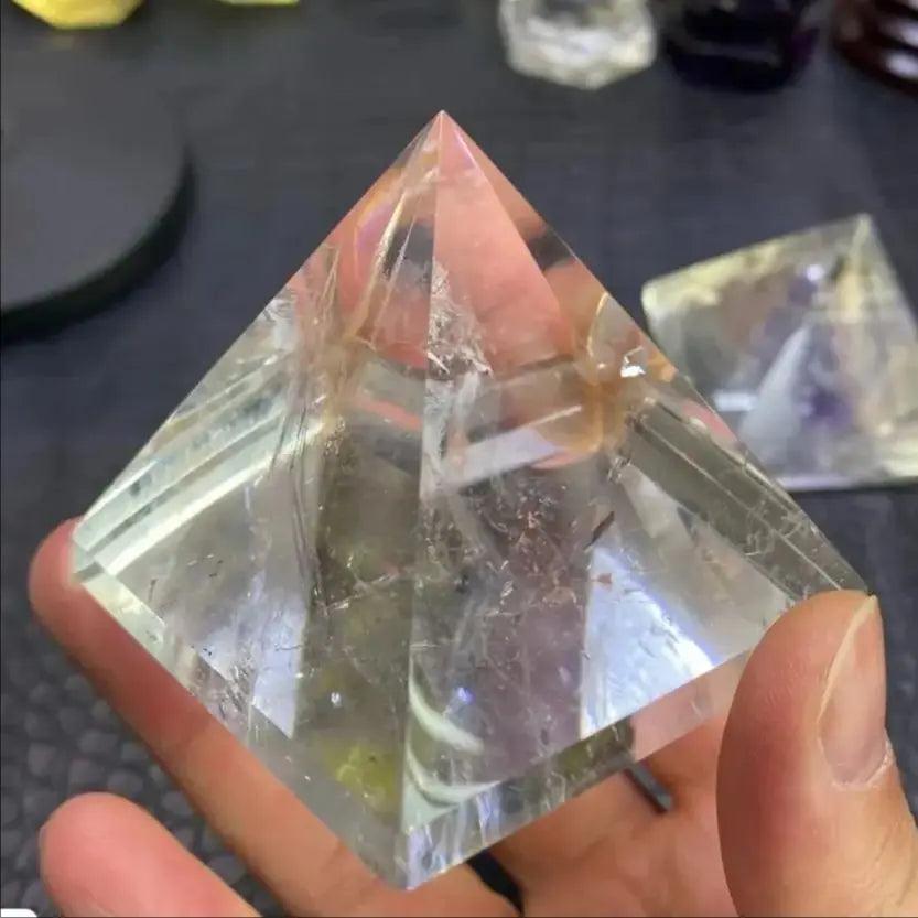 Clear natural quartz crystal pyramid held in hand, perfect for chakra healing and meditation.