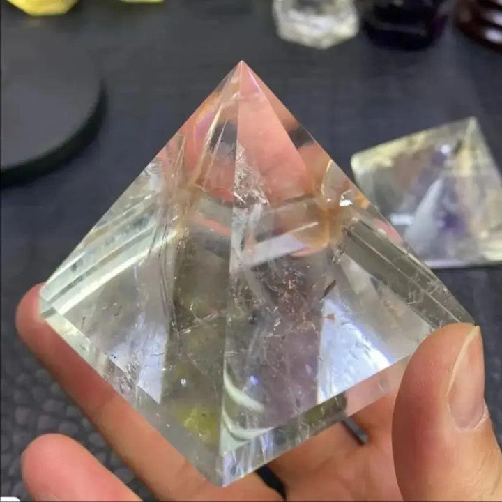 Clear natural quartz crystal pyramid held in hand, perfect for chakra healing and meditation.