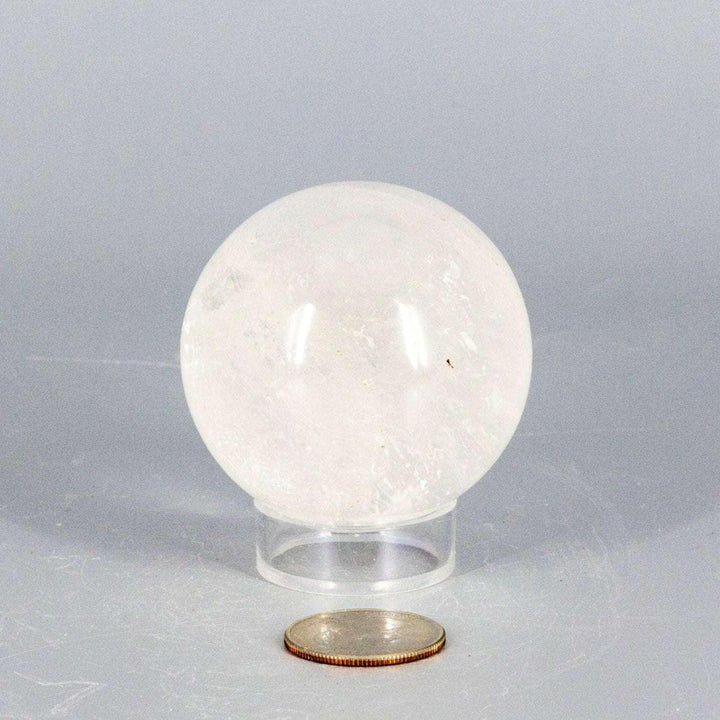 Natural Quartz Sphere Master Healer, 53-55mm, clear polished crystal ball on stand, with coin for scale.