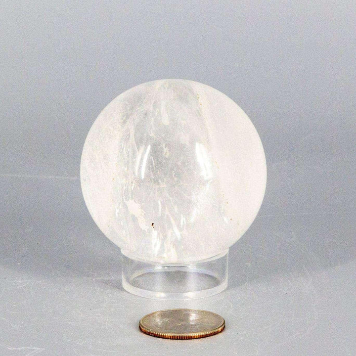 Natural Quartz Sphere Master Healer, 53-55mm, clear polished crystal with unique inclusions on a stand.