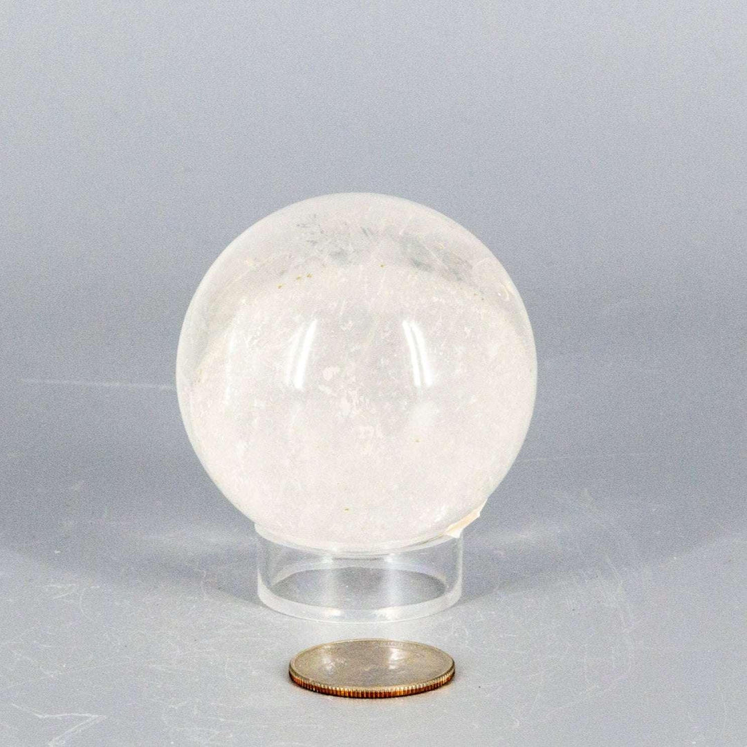 Natural Quartz Sphere Master Healer, 53-55mm, clear polished crystal ball on stand, with coin for scale.