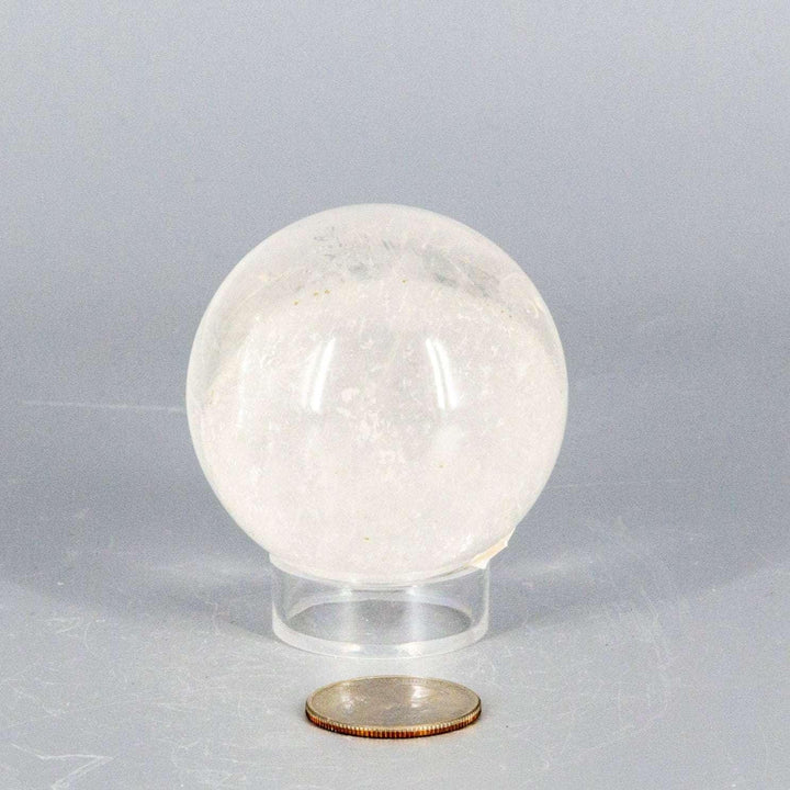 Natural Quartz Sphere Master Healer, 53-55mm, clear polished crystal ball on stand, with coin for scale.