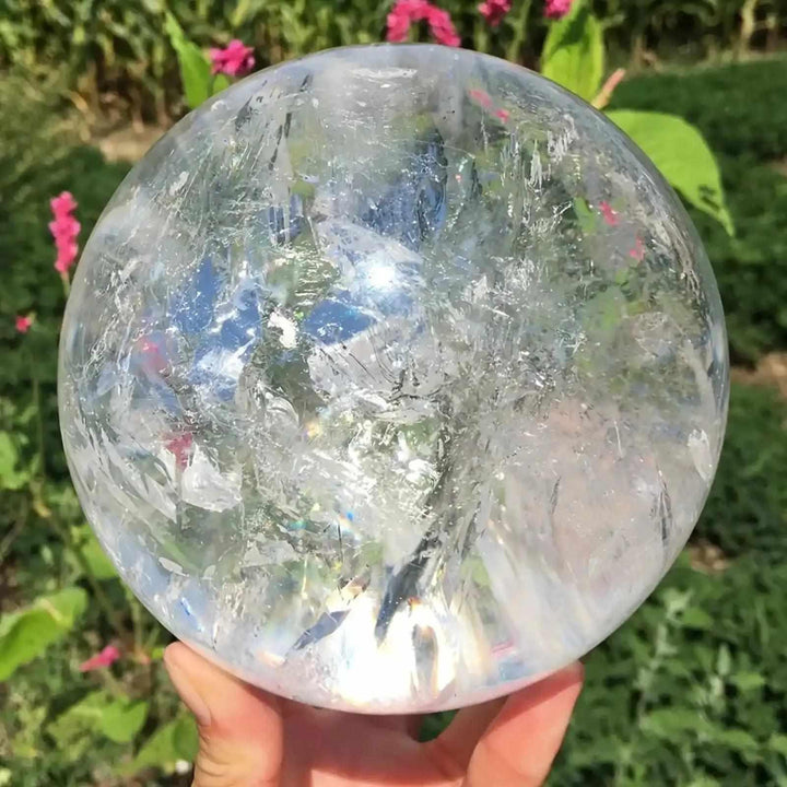 Polished Clear Quartz crystal sphere with internal veils and reflective layers, perfect for Crown Chakra meditation.