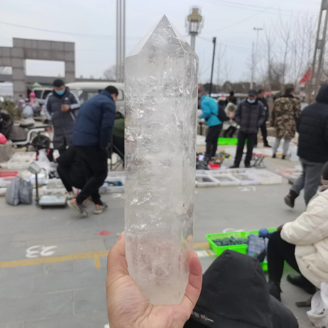 Substantial, clear quartz crystal tower obelisk, polished to a high finish, held in a hand.