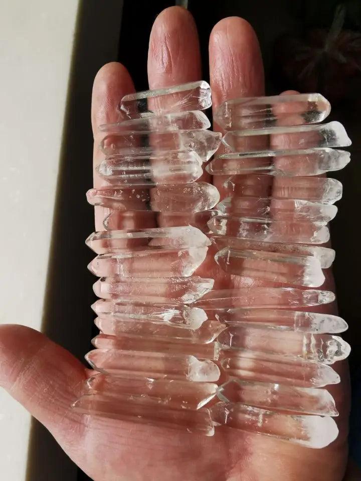 Clear Quartz Lemurian Seed Crystal Natural Points, 20 raw, terminated points with horizontal striations, held in a hand.