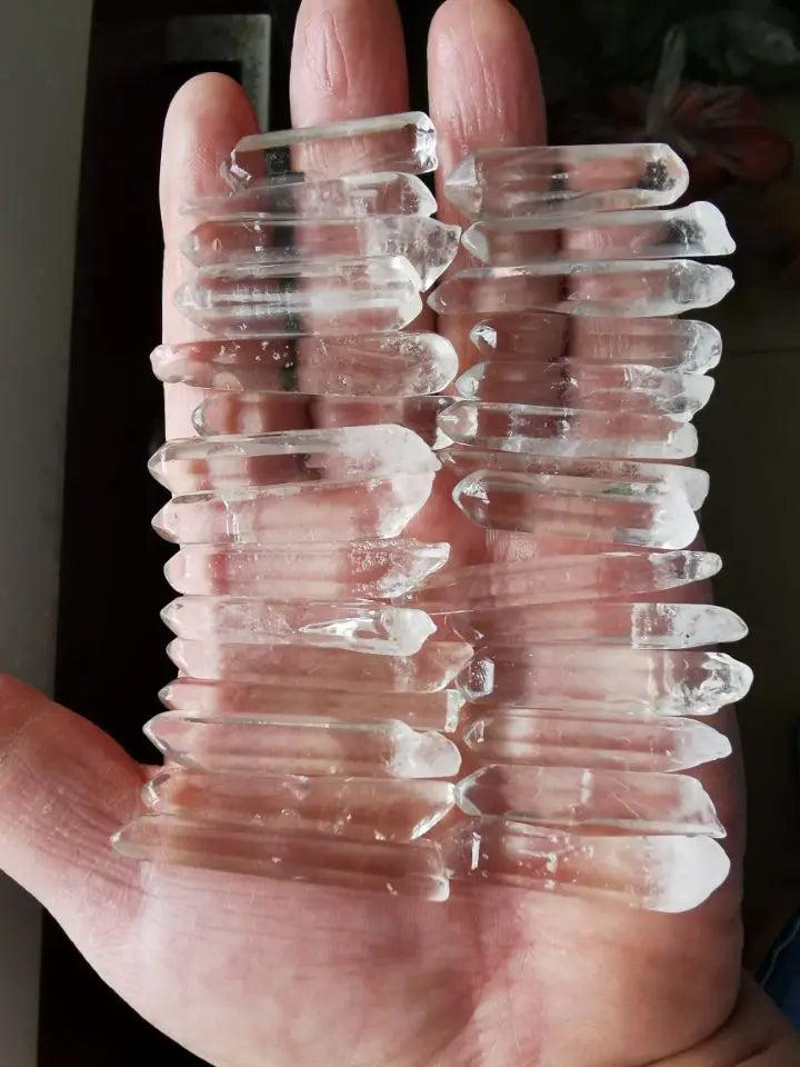 Clear Quartz Lemurian Seed Crystal Natural Points, 20 raw, terminated points with horizontal striations, held in a hand.