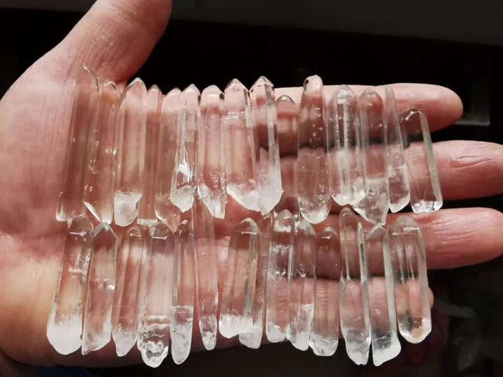 Hand holding 20 clear quartz Lemurian Seed Crystal natural points, showcasing exceptional clarity and horizontal striations.
