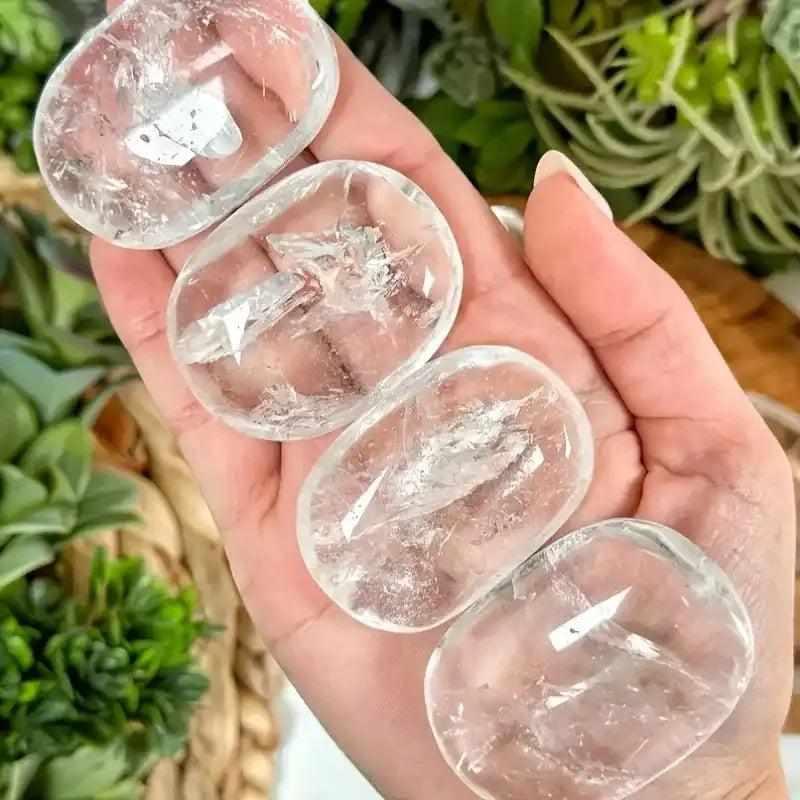 Smooth, polished Clear Quartz palm stones with natural inner textures, perfect for meditation and Crown Chakra healing.