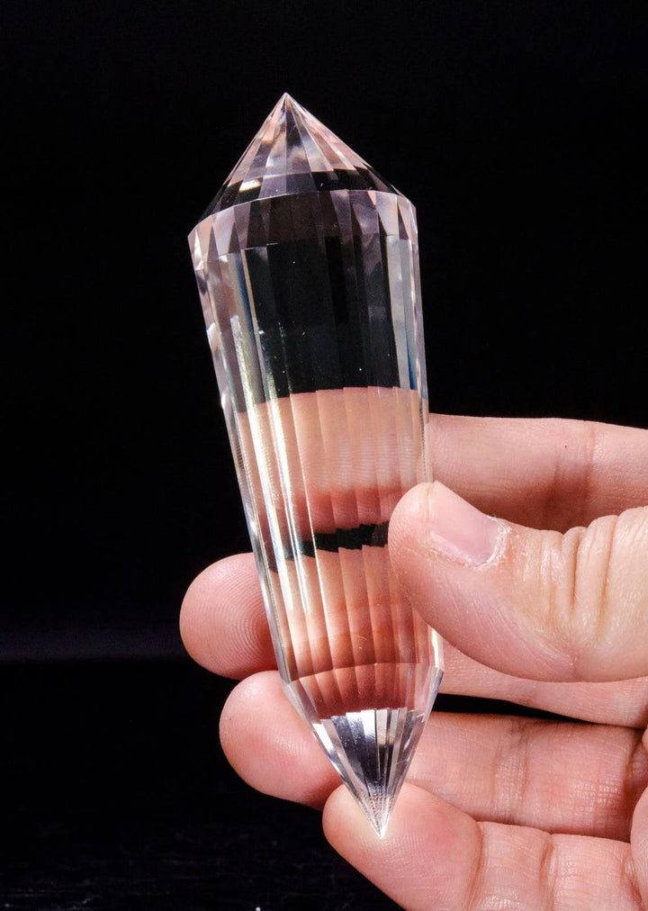 Clear quartz crystal Vogel-style wand, 24-sided double point, held in hand for spiritual healing.