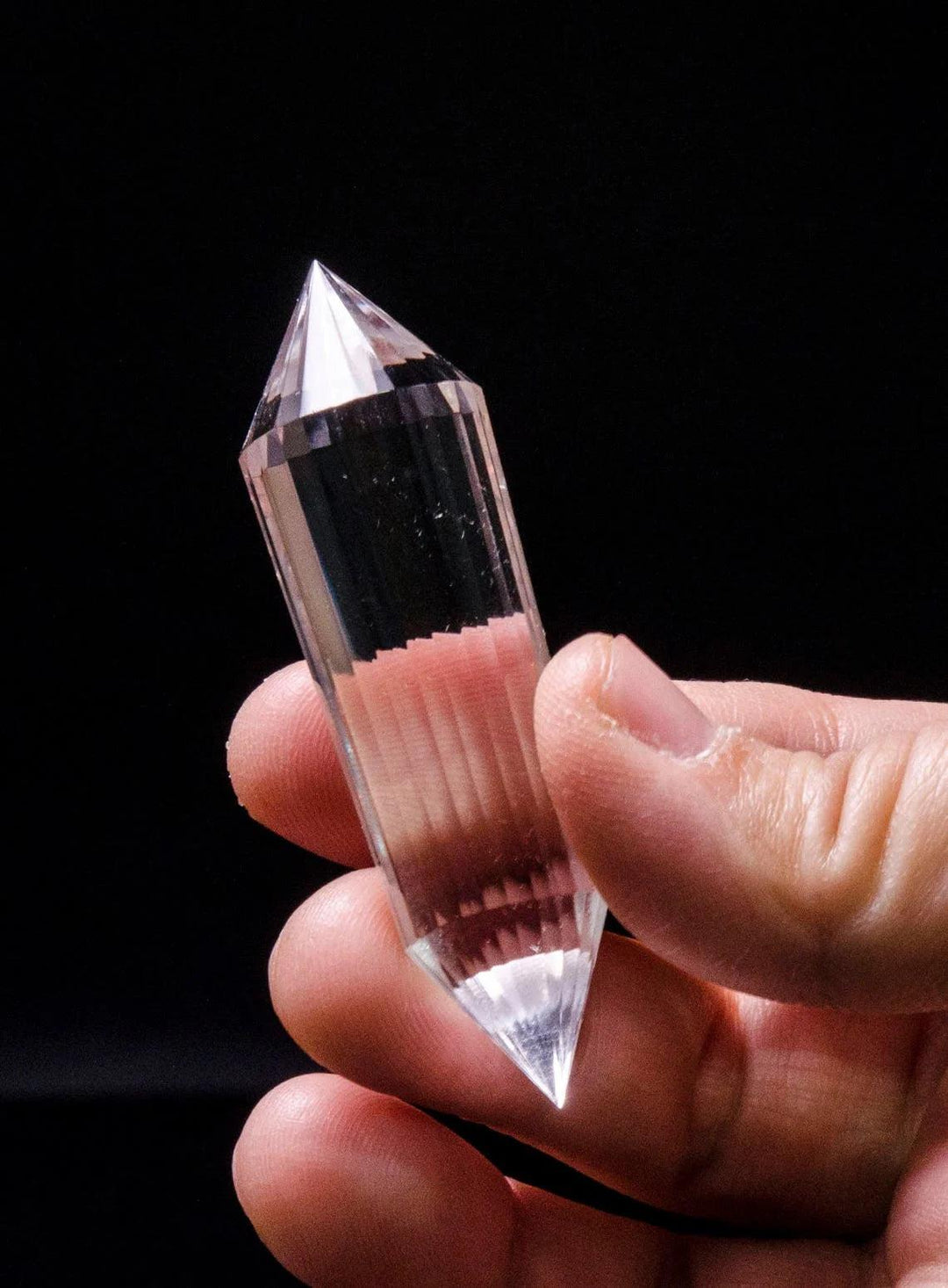 Hand holding a clear quartz Vogel wand, 24-sided double point, for focused healing and manifestation.