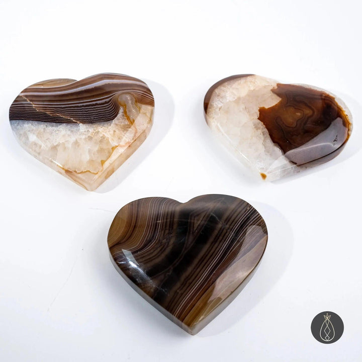 Three polished Coffee Agate crystal hearts from Crystal Destiny, showcasing warm caramel, chocolate, and cream swirls.