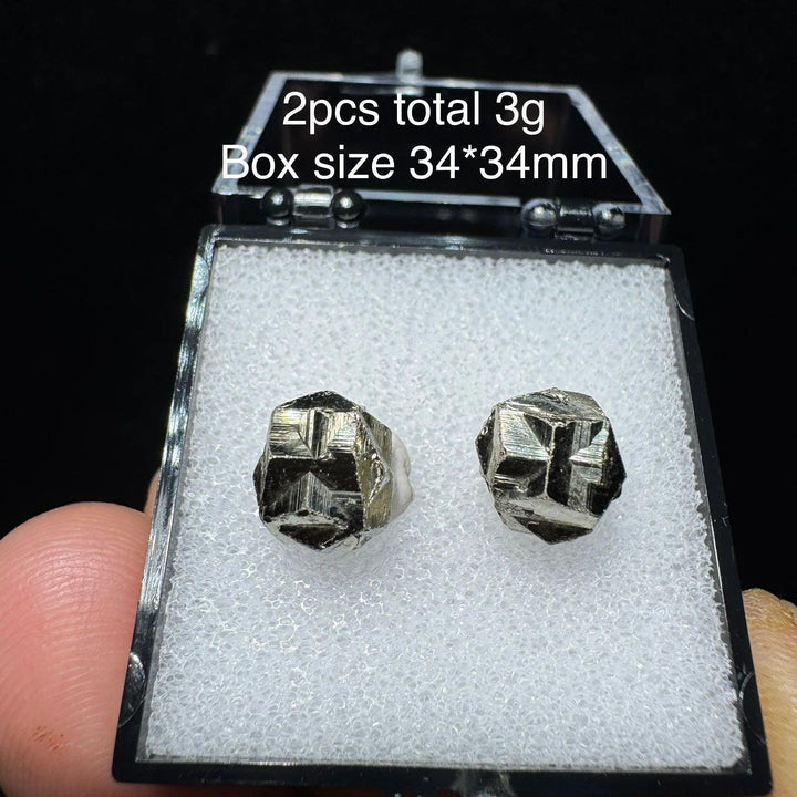 Two natural Colombian cross pyrite crystals in a 34x34mm display box, featuring metallic luster for healing and home decor.
