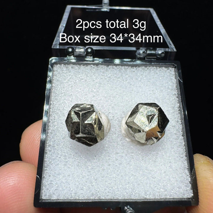 Two natural Colombian cross pyrite crystals in a 34x34mm display box, featuring metallic luster for healing and home decor.