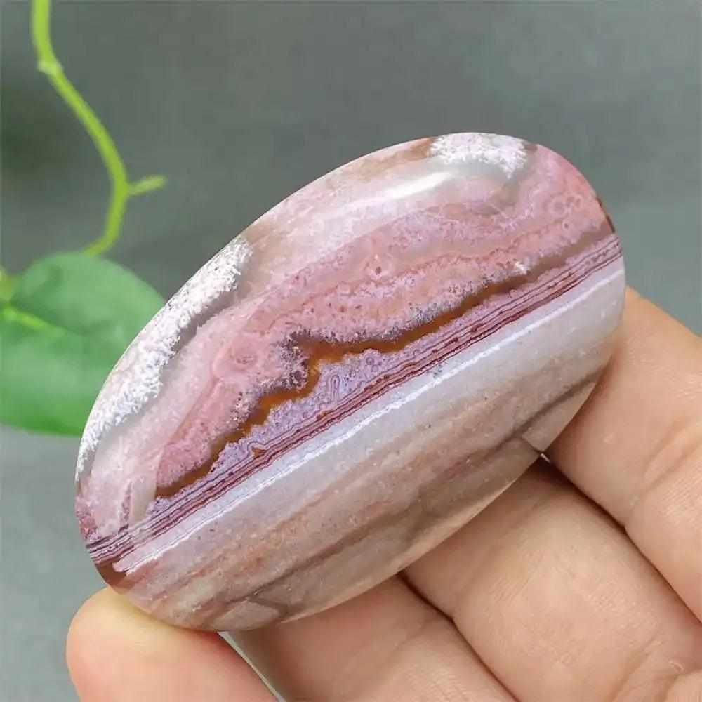 Polished Crazy Lace Agate palm stone featuring swirling red, brown, and cream lace bands for grounding and joy.