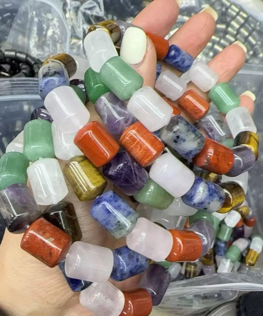Hand holding a vibrant assortment of barrel-cut natural crystal beads for the Crystal Big Beads Bracelet.