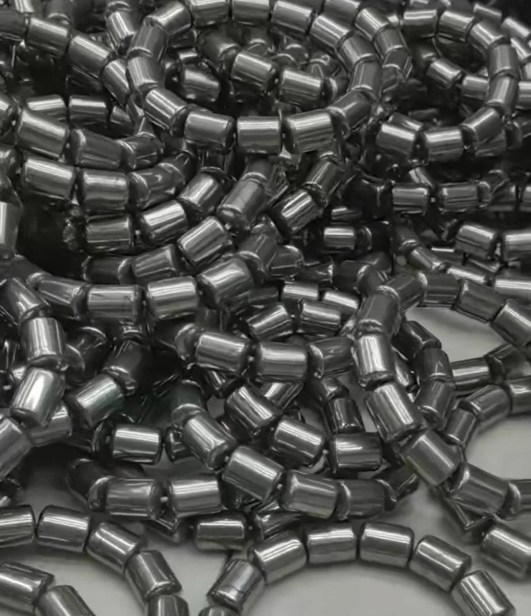 Pile of shiny, dark gray barrel-cut beads for a Crystal Big Beads Bracelet, ready for daily intention work.