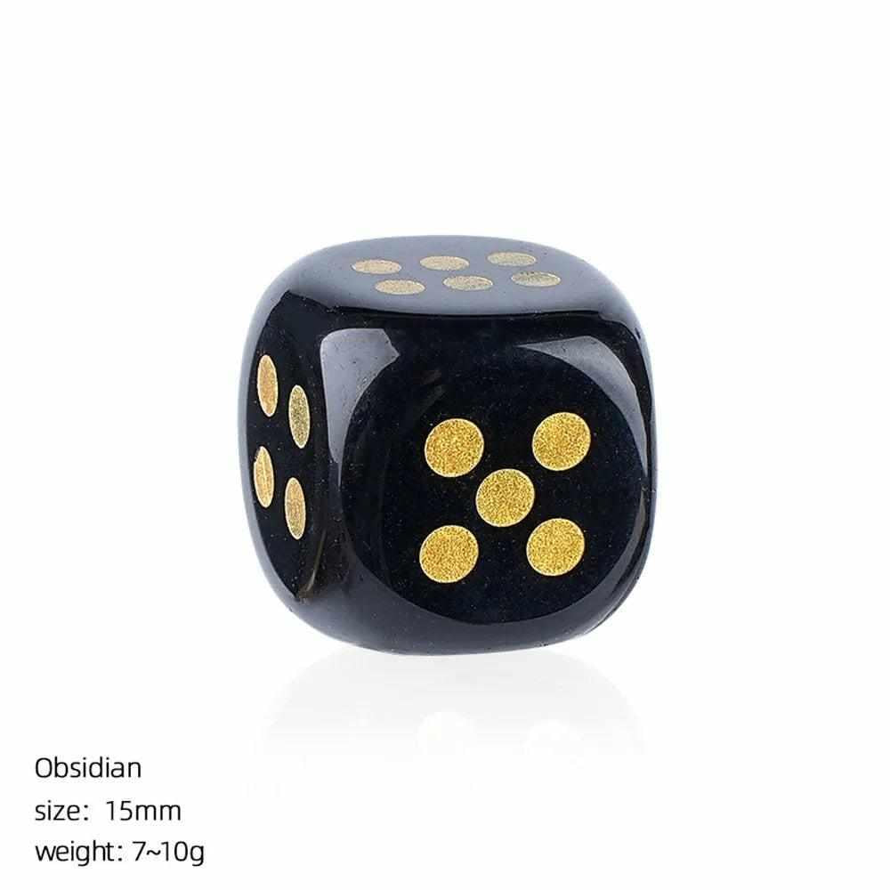 15mm Obsidian crystal carved die with rounded corners and gold pips, offering grounding energy for gaming or altars.