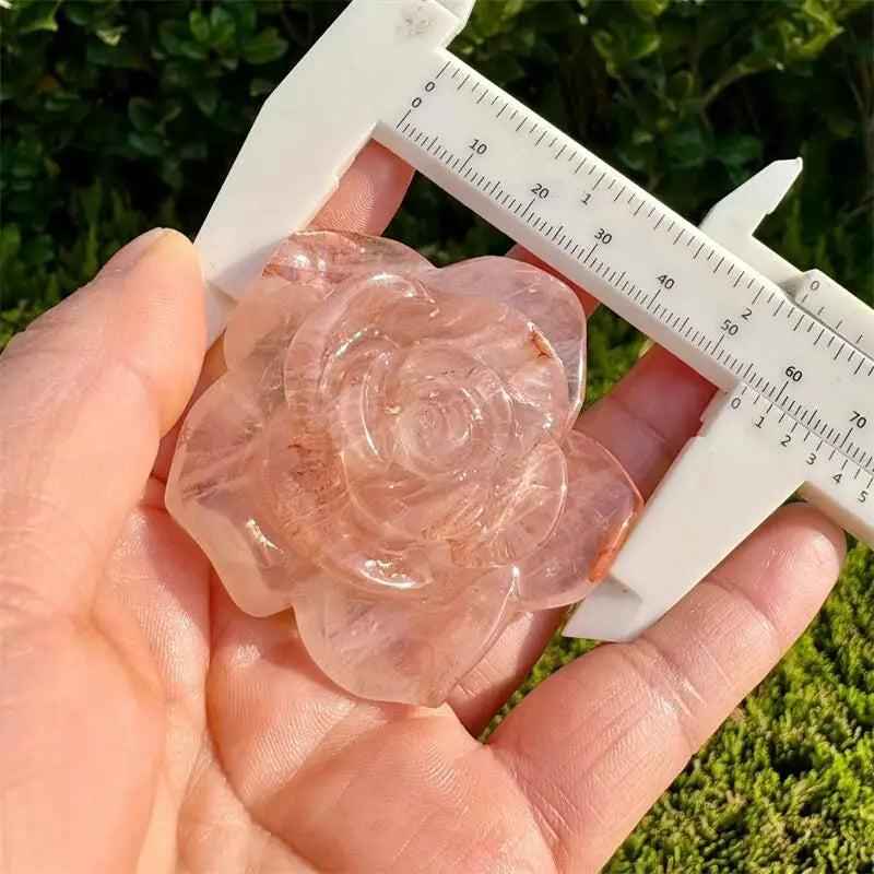 Red Fire Quartz flower figurine, a delicate crystal carving for Heart Chakra healing, held to show its size and color.