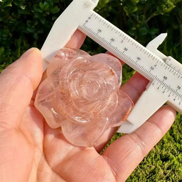 Red Fire Quartz flower figurine, a delicate crystal carving for Heart Chakra healing, held to show its size and color.