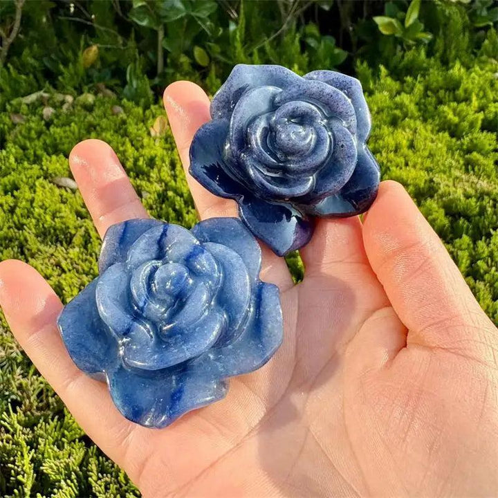 Two blue aventurine crystal flower figurines carved with delicate petals, held in a hand to showcase their natural energy.