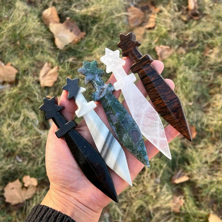 Hand-carved crystal sword letter openers: black, striped, mossy green, clear, and dark wood-grain.