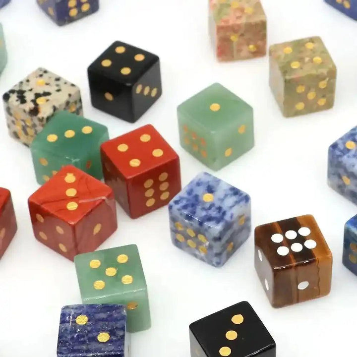 Hand-carved natural gemstone dice with gold pips, showcasing various stones like Obsidian, Rose Quartz, and Tiger Eye.