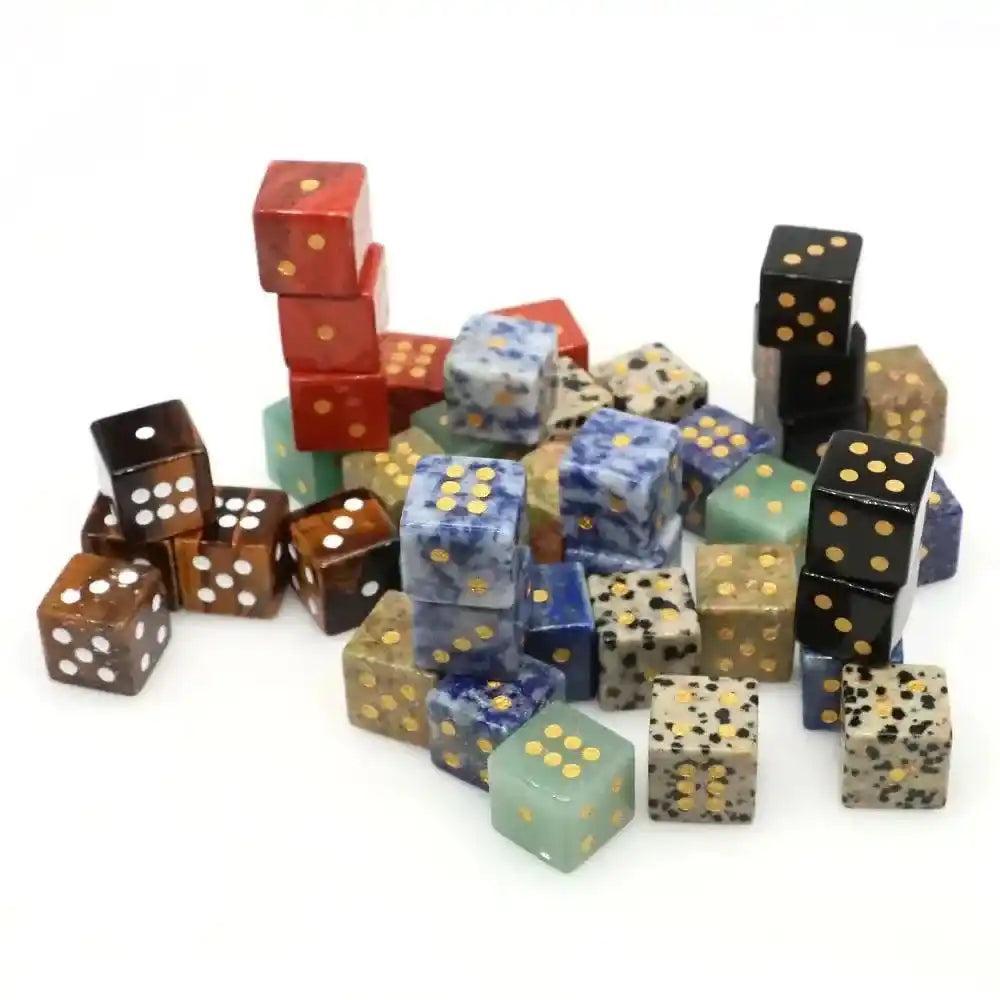 Assorted hand-carved natural gemstone crystal dice with gold pips, including Red Jasper, Lapis Lazuli, and Dalmatian Jasper.