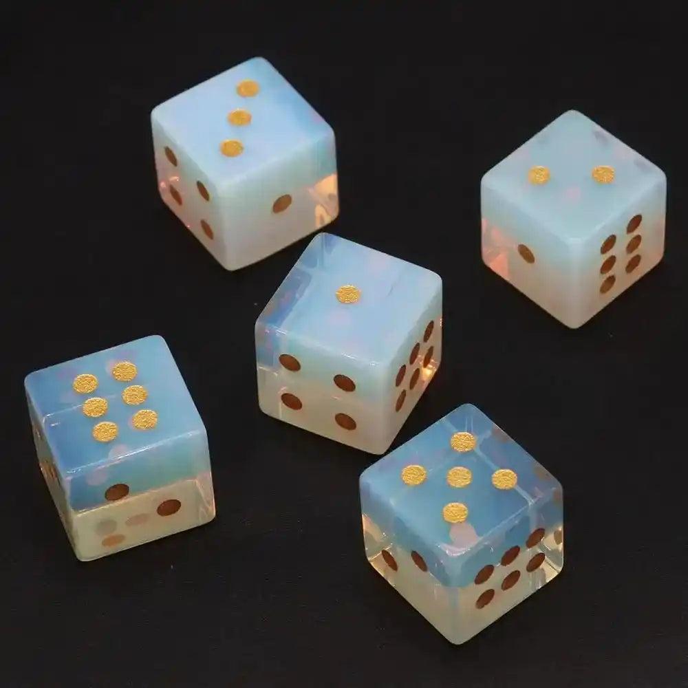 Five 16mm hand-carved Opalite Crystal Dice with gold-painted pips, glowing with soft blue and white hues.