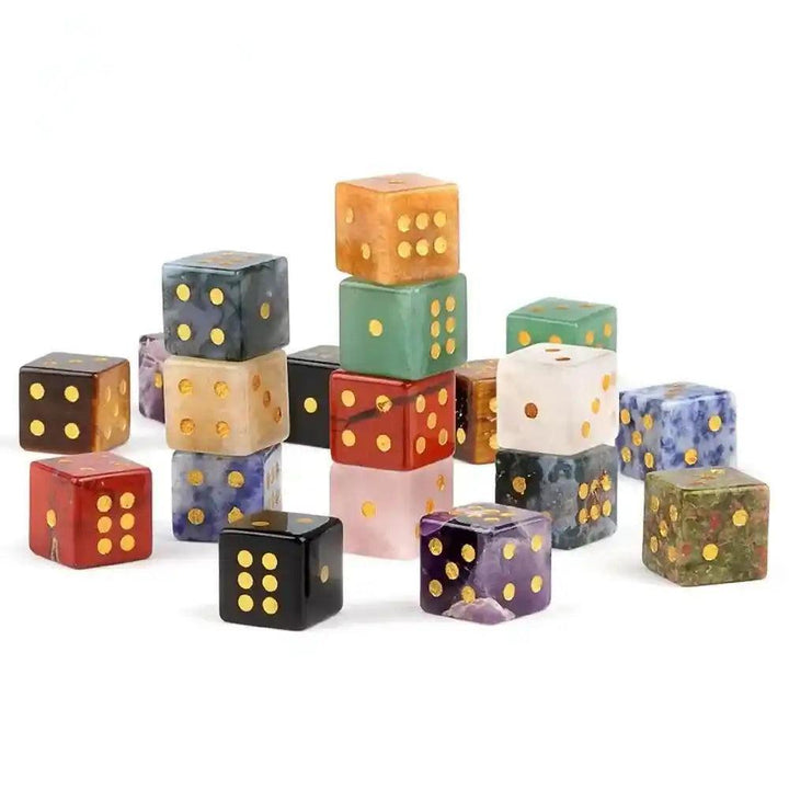 Assorted 16mm hand-carved natural gemstone crystal dice with gold pips, including Rose Quartz, Tiger Eye, and Obsidian.
