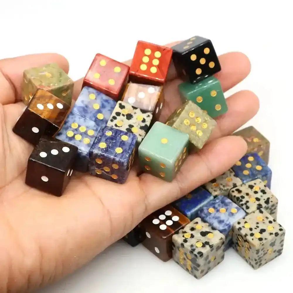 Hand-carved natural gemstone crystal dice in various colors like Lapis Lazuli and Tiger Eye, with gold pips.