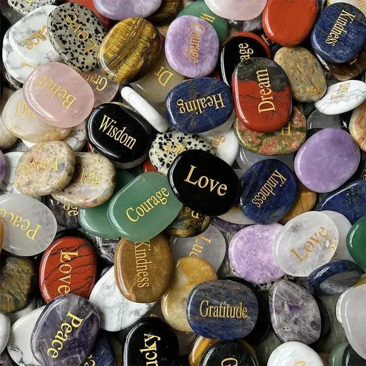 Assorted polished crystal palm stones with engraved inspirational words like "Love," "Courage," and "Wisdom.