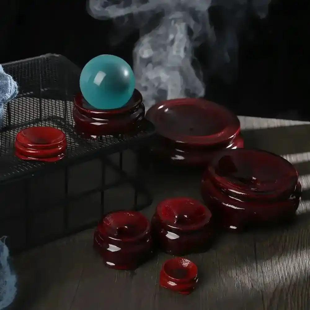 Assorted dark red wooden crystal sphere display stands showcasing a vibrant blue crystal sphere.
