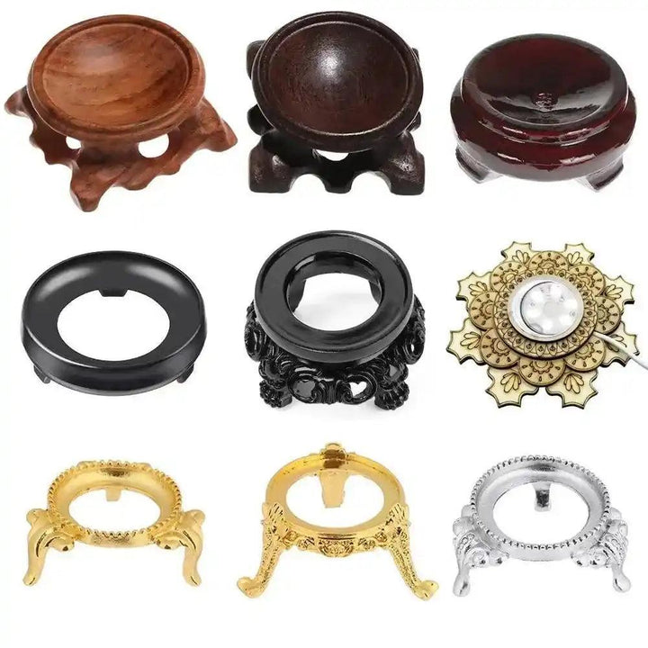 Assorted crystal sphere display stands in wood, black metal, gold, silver, and a light-up mandala design.