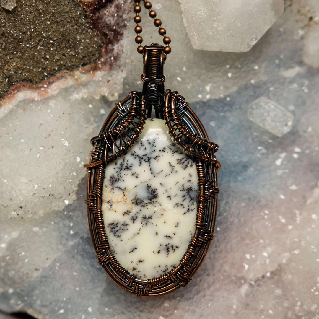Dendritic Agate wire wrap pendant by Crystal Destiny, featuring a white oval stone with black fern-like inclusions in copper.