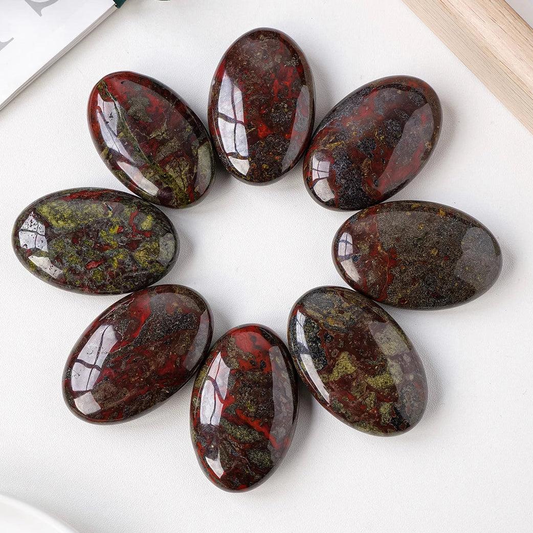Polished Dragon Blood Jasper palm stones featuring deep green and rich red patterns for courage and grounding energy.