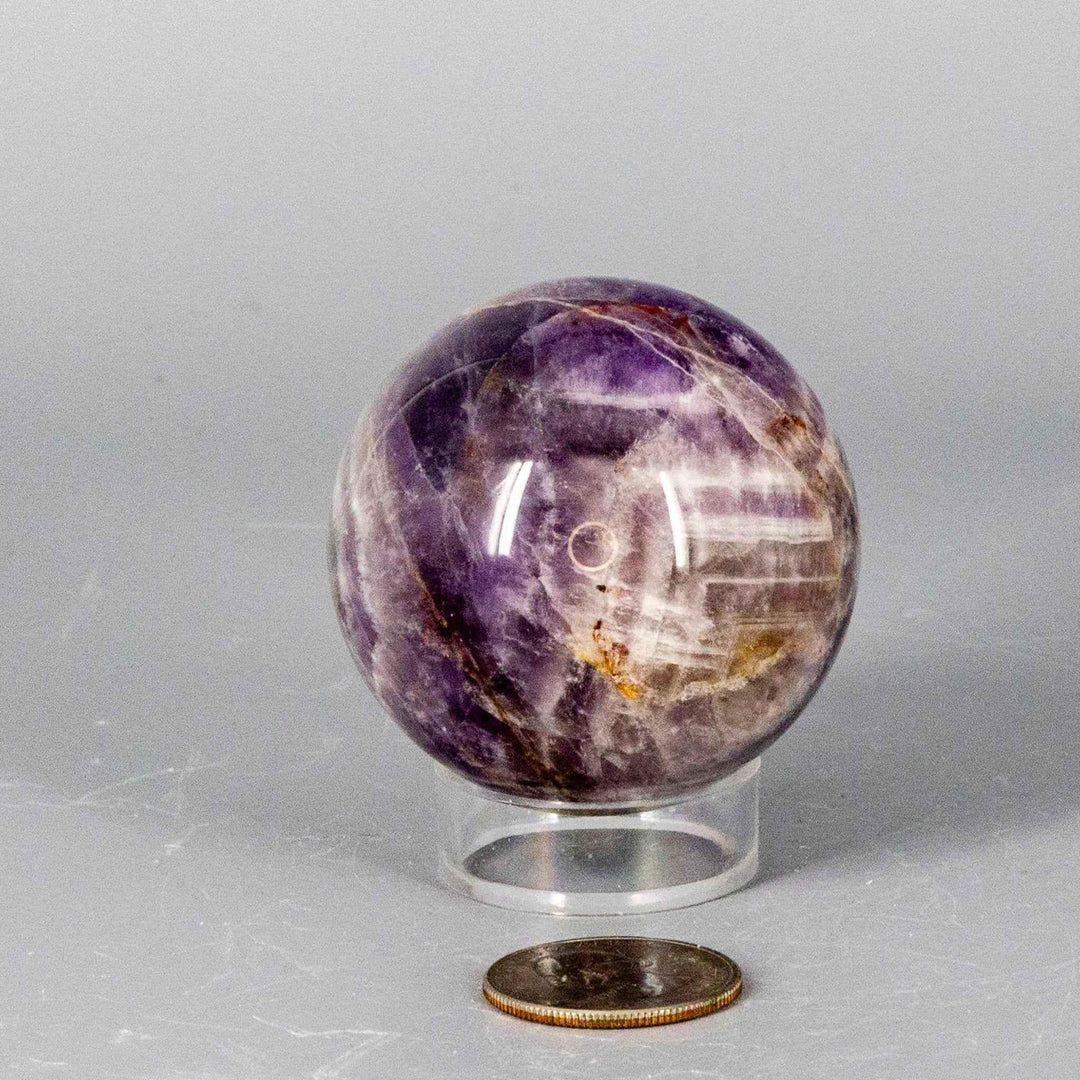 Dream Amethyst Sphere (51-57mm) with flowing purple and white bands, radiating calming energy for sleep and meditation.