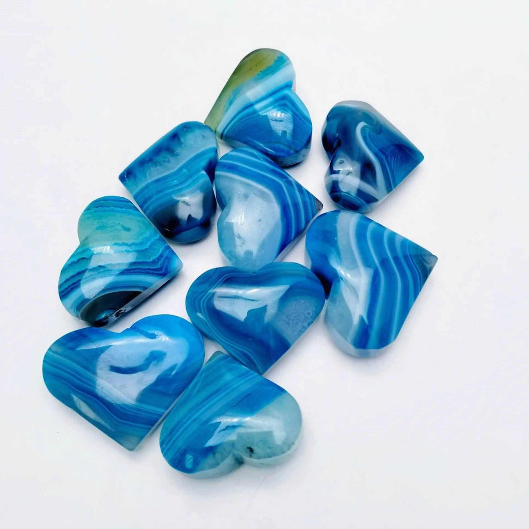 Polished dyed blue agate hearts featuring vibrant natural banding, perfect for Throat Chakra healing and calm meditation.