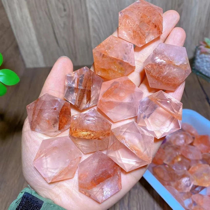 Hand holding multiple polished Fire Quartz hexagram star pendants, showcasing their activating, grounding energy.