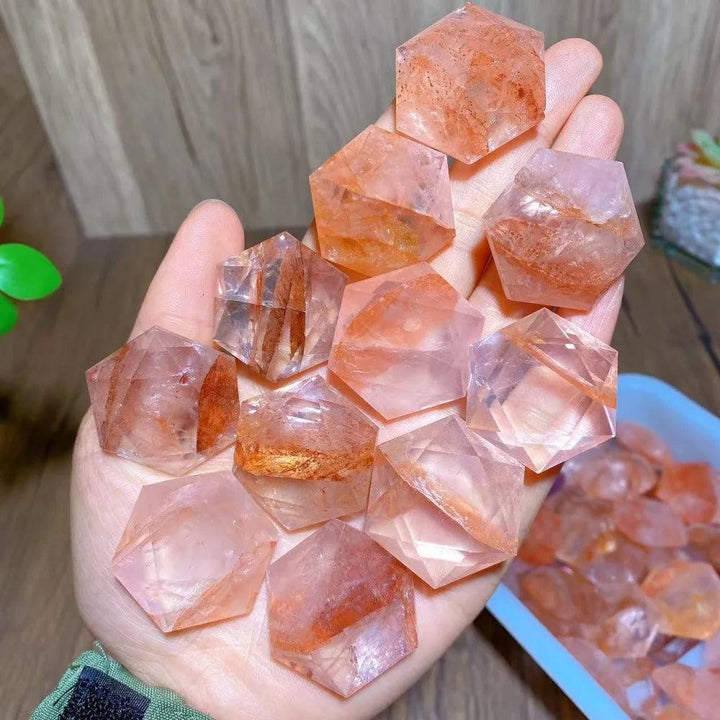 Hand holding several polished Fire Quartz Hexagram Star pendants, showcasing their activating, grounding energy.