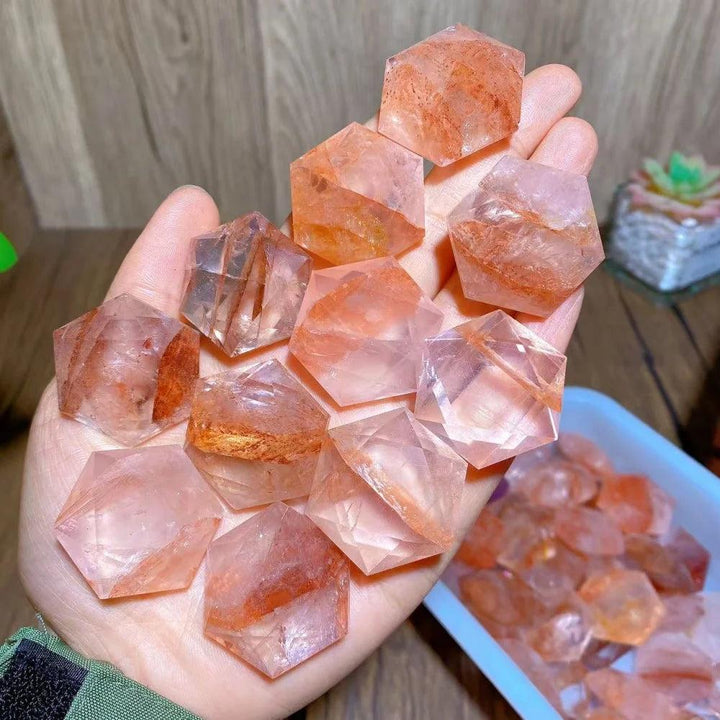 Hand holding vibrant Fire Quartz hexagram star pendants, showcasing their amplifying clarity and activating energy.