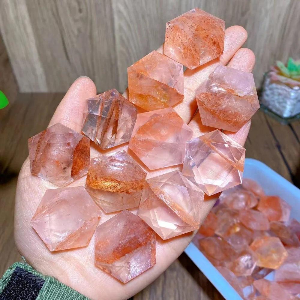 Hand holding multiple polished Fire Quartz hexagram star pendants, showcasing their red and clear hues.