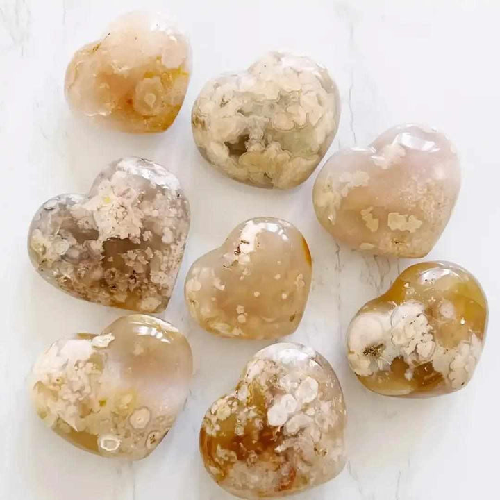 Polished Flower Agate hearts featuring soft pink and white floral plumes for Heart Chakra healing and self-love.