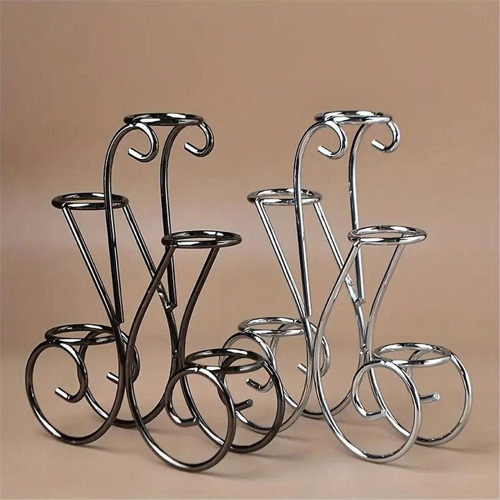 Two metal flower-petal five-sphere crystal display stands, one silvery and one gray black, on a beige background.