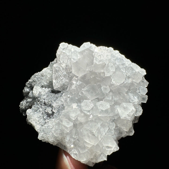 Sparkling white raw columnar calcite crystal cluster healing stone specimen on a dark background.