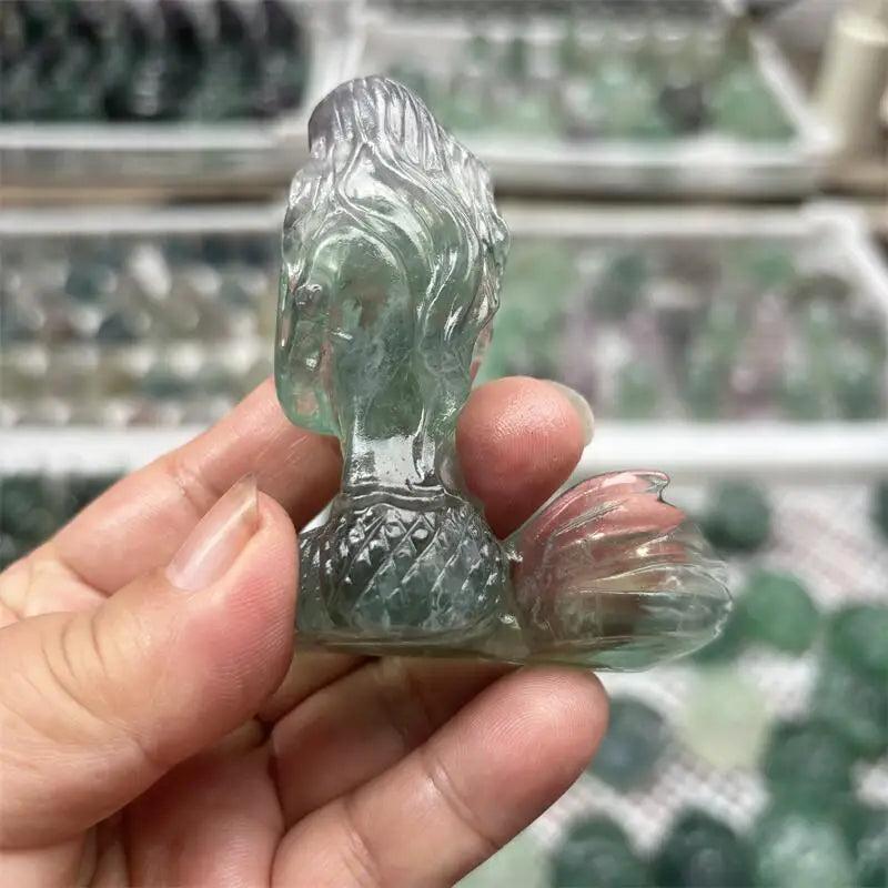 Hand-carved natural fluorite mermaid crystal figurine with translucent green and purple hues for healing and home decor.