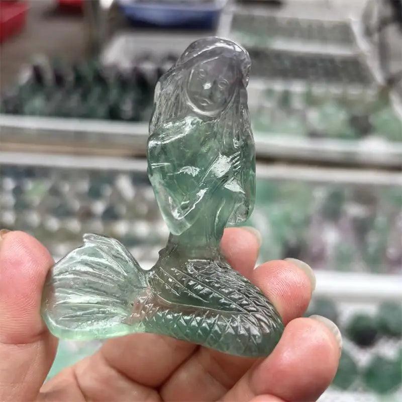 Hand-carved natural fluorite mermaid crystal figurine with translucent green and purple hues for healing and home decor.